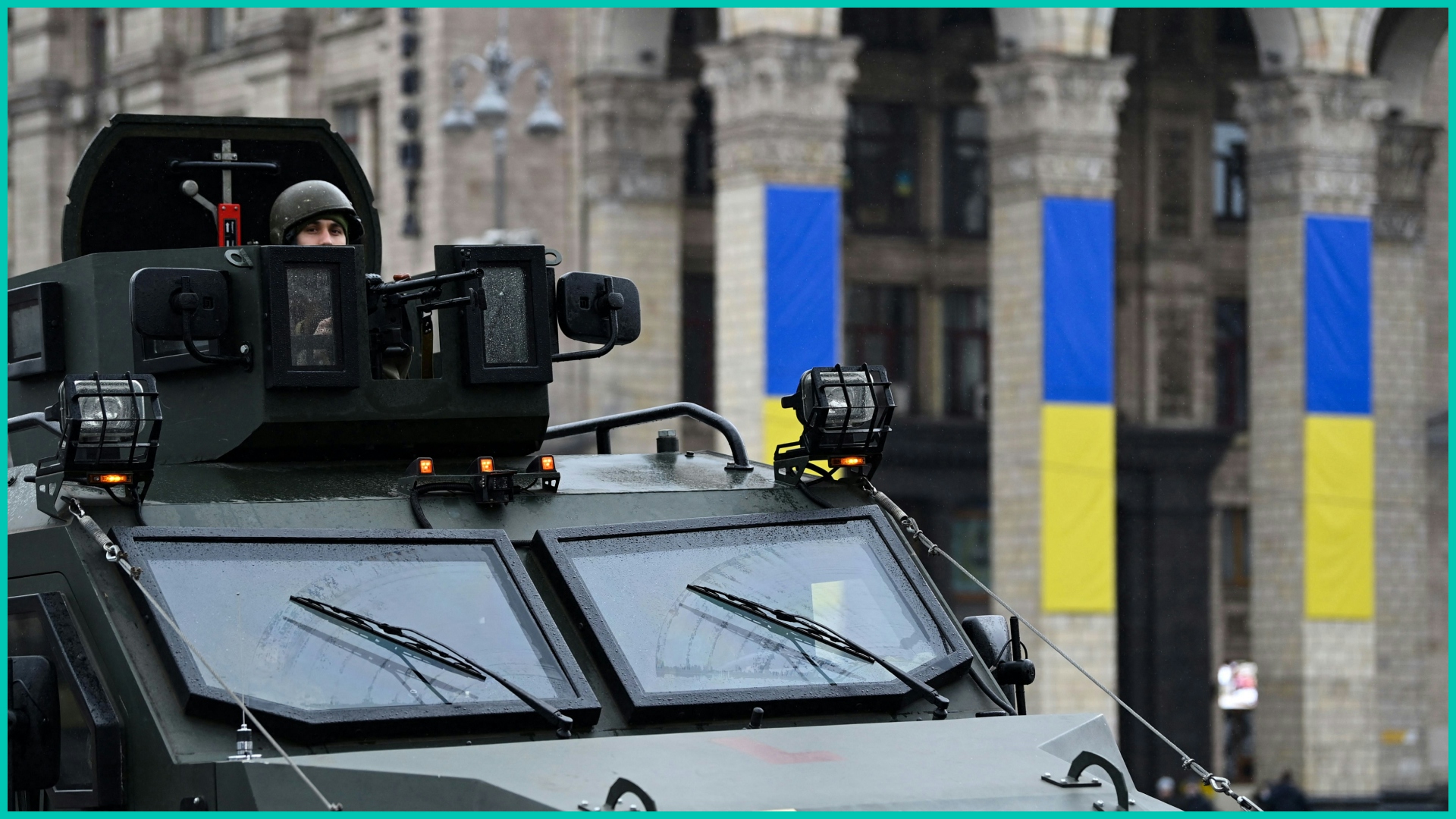 A Ukrainian serviceman rides atop a military vehicle past Independence square in central Kyiv