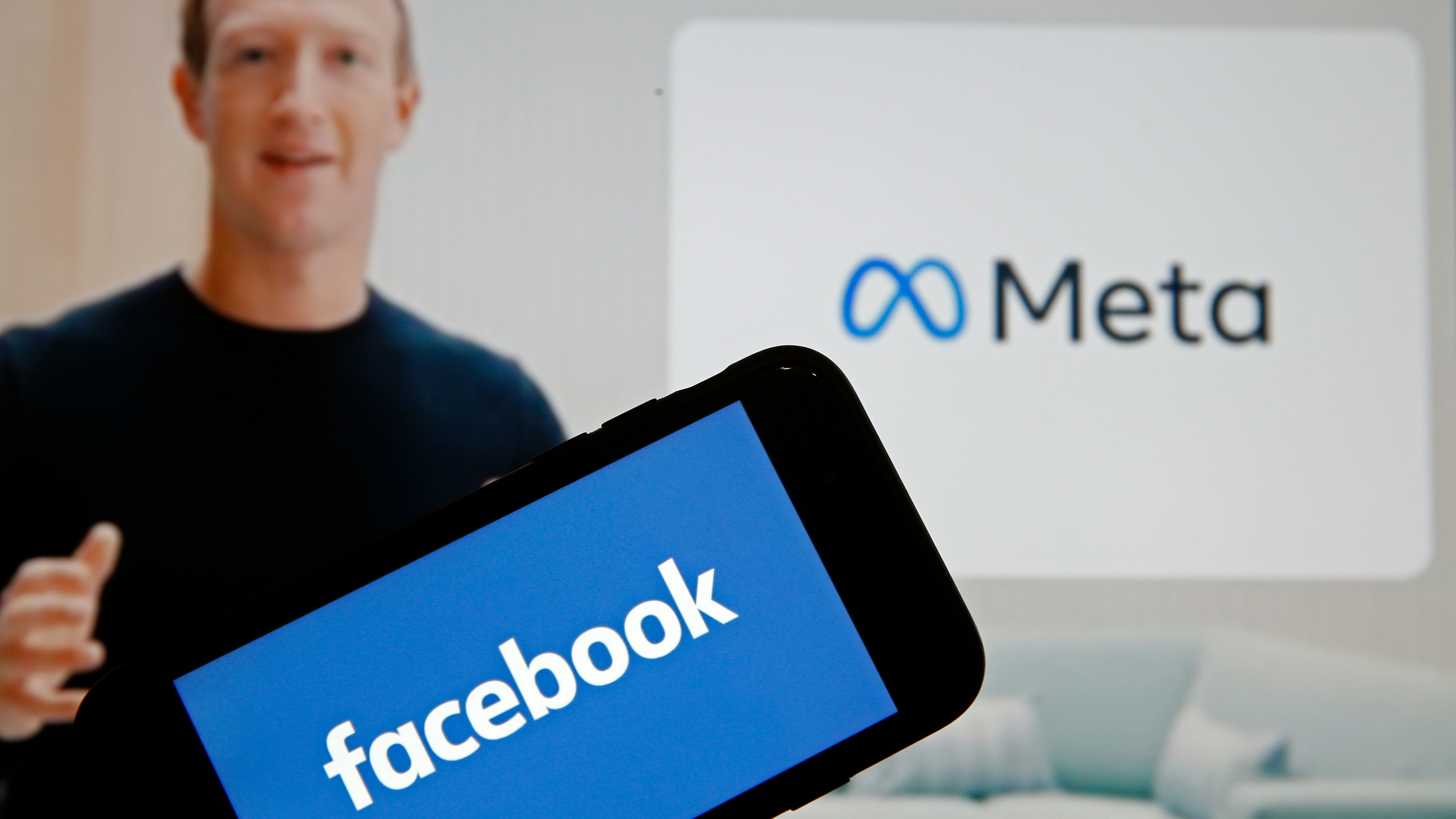 In this photo illustration, the Facebook logo is displayed on the screen of an iPhone in front of a Meta logo 