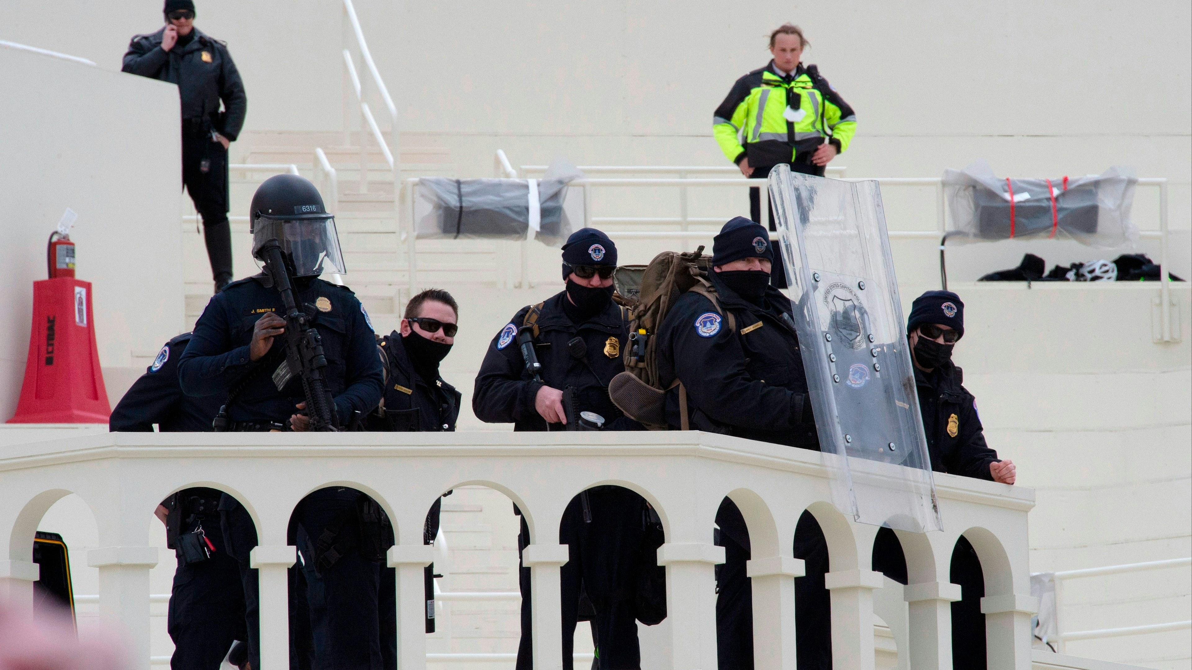 Police watch as protesters surround the US Capitol Building and begin to storm it after a rally in support of US President Donald Trump in Washington, DC on January 6, 2021.