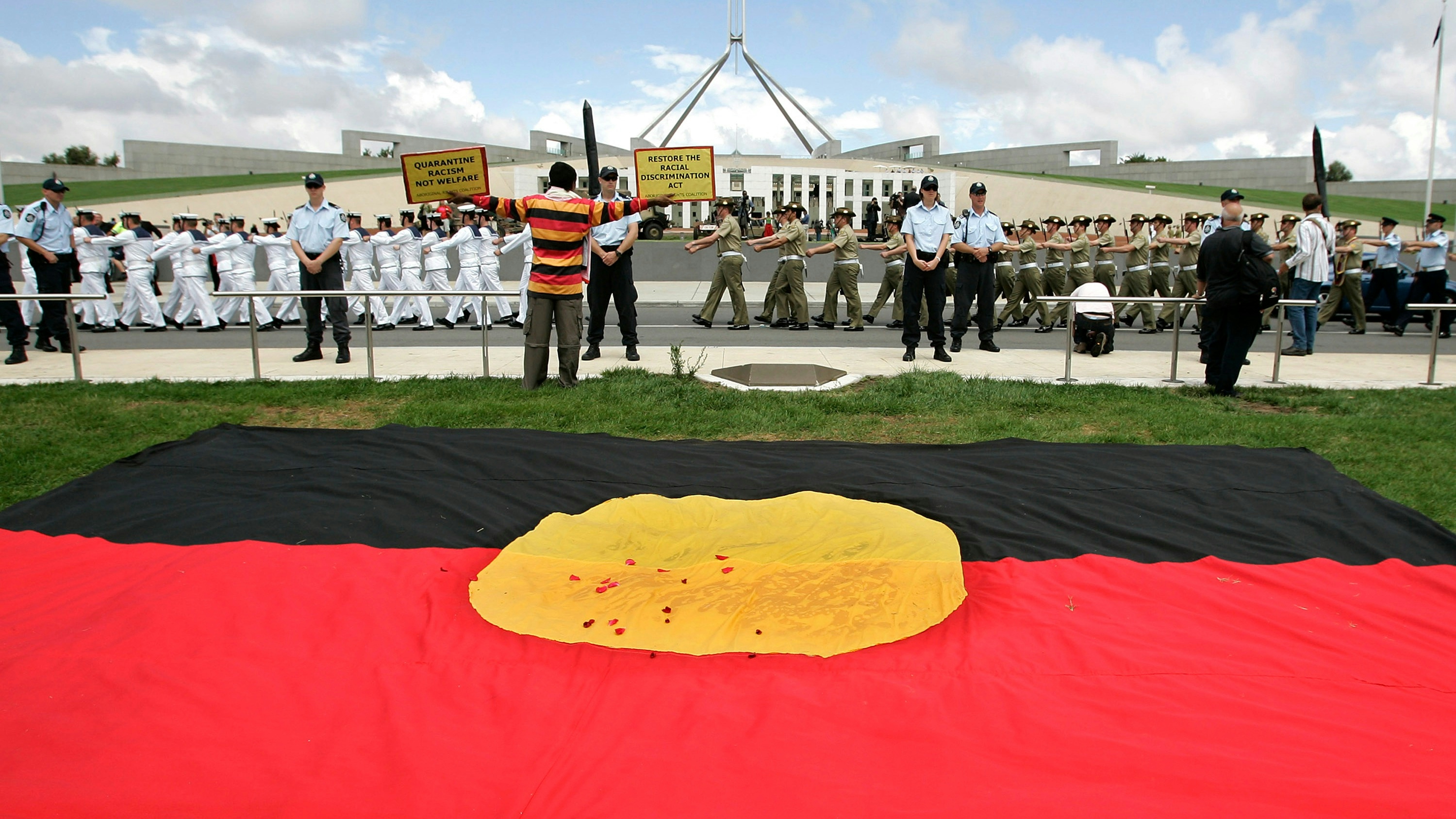 An Aborigonal protester sits outside Parliament House during the opening of the 42nd Parliament 