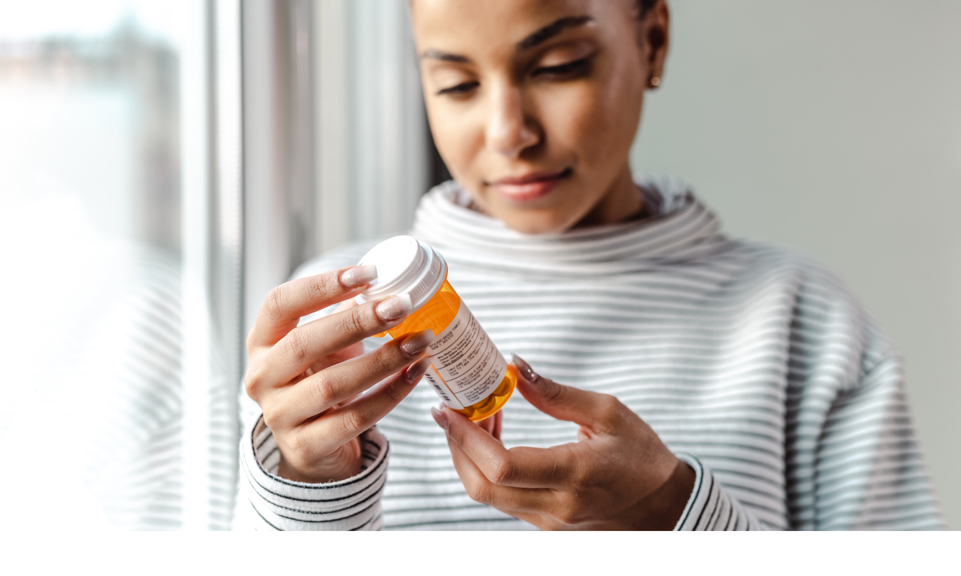 A woman looking at a bottle of pills