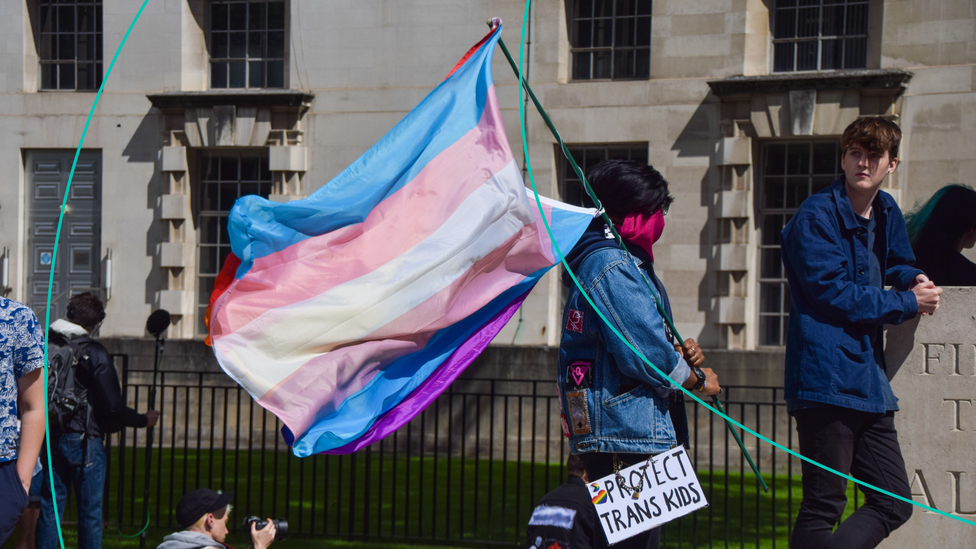 A protester holds a Trans Pride flag and a 'Protect Trans Kids' placard during the trans rights demonstration
