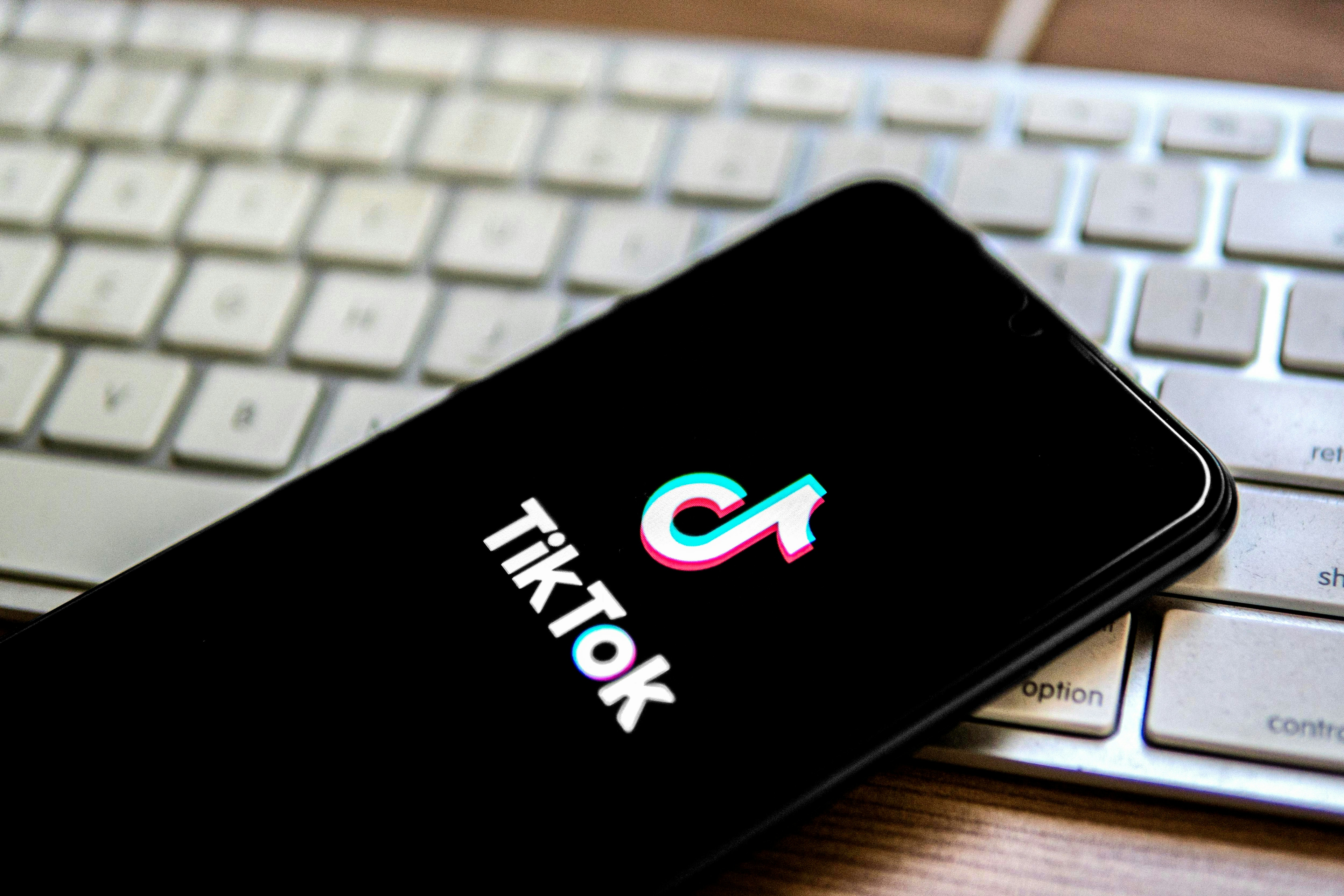 A phone laying on a keyboard with the TikTok logo on the screen