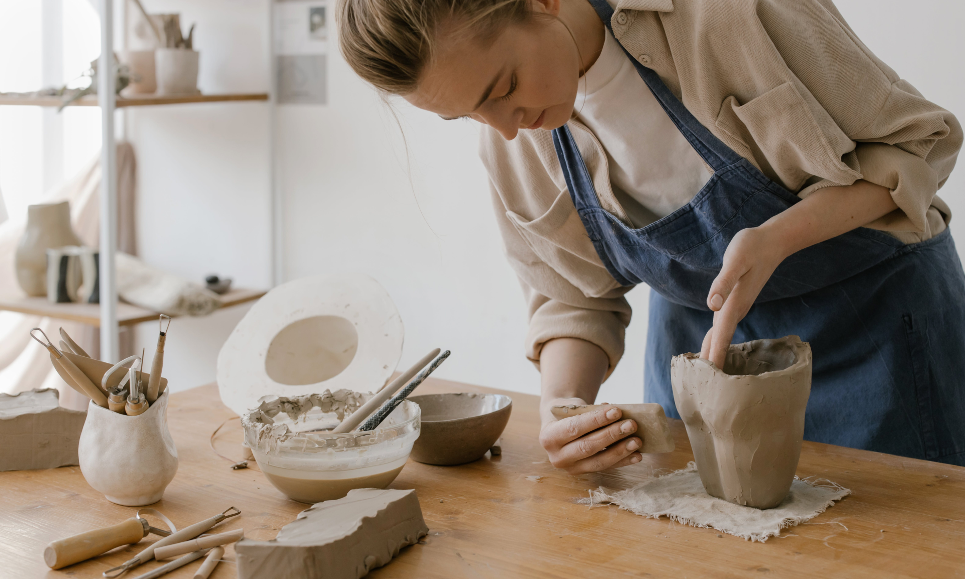 Woman sculpting a vase with her hands in a pottery studio