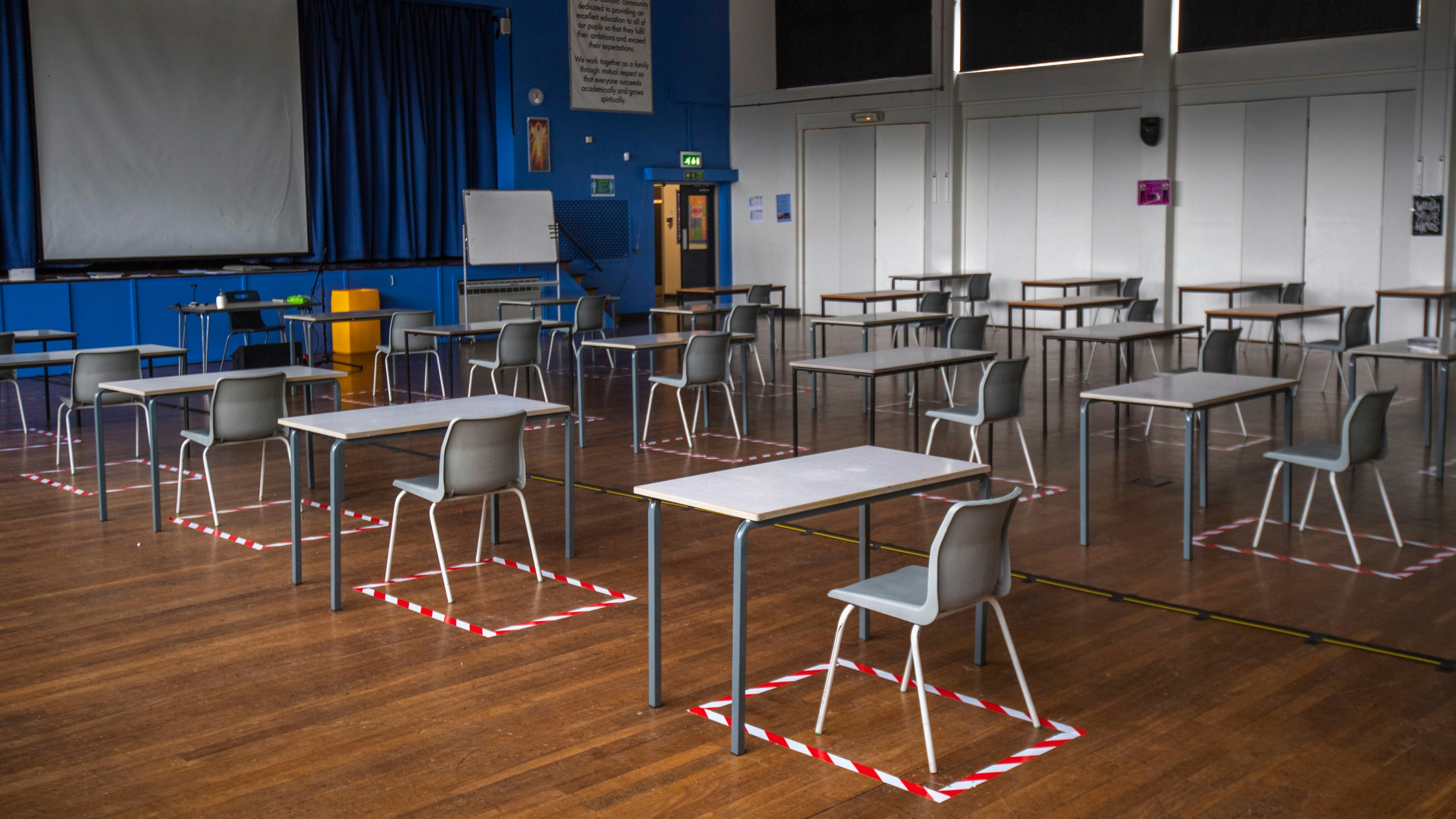 Socially distanced desks are set out for lesson in the hall at All Saints Catholic College in Dukinfield, England