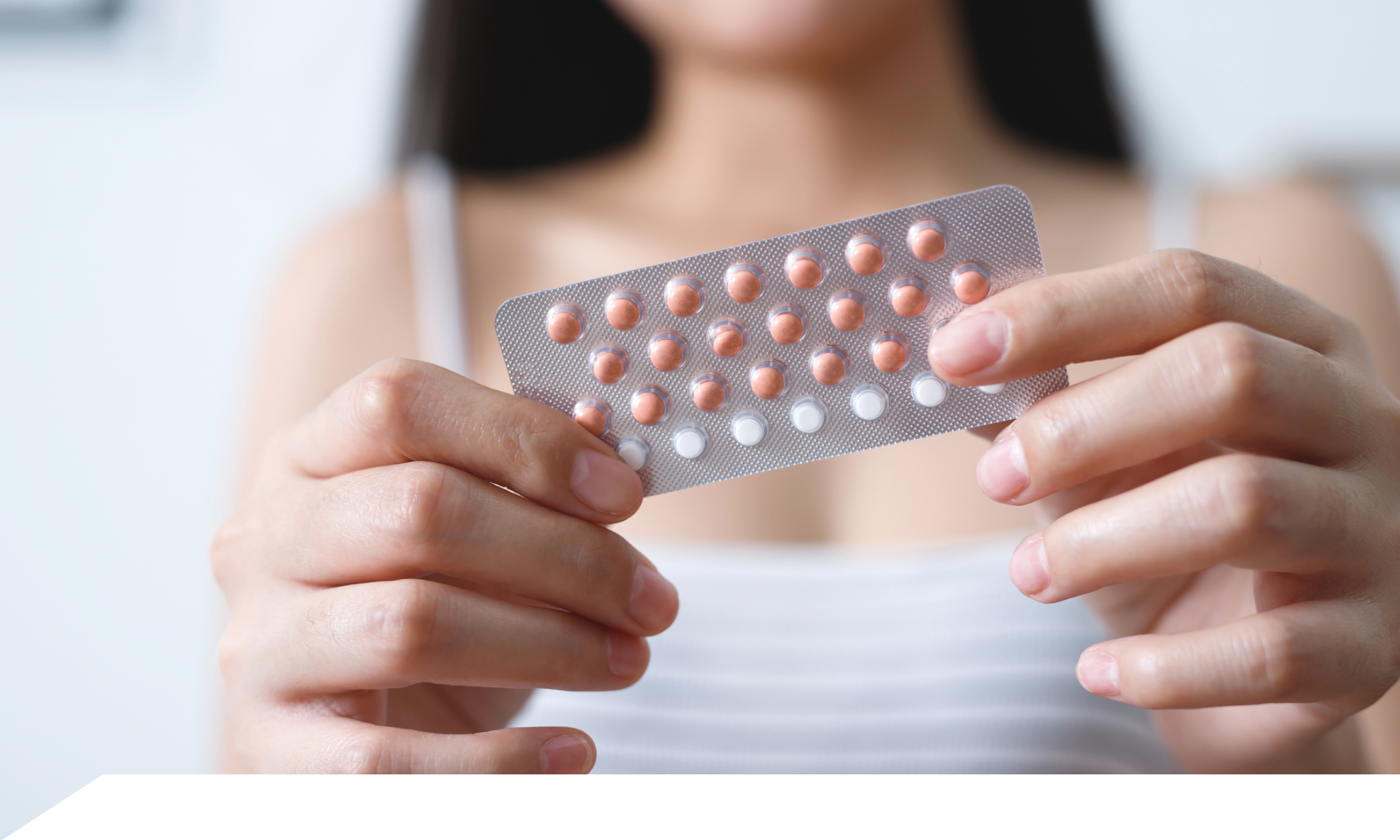 A woman holding up a birth control pill packet