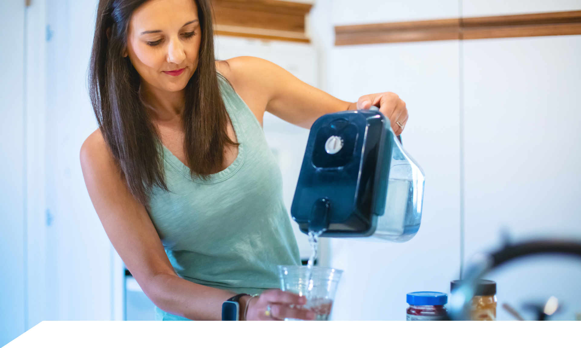 A woman pouring a glass of water from a filtered pitcher