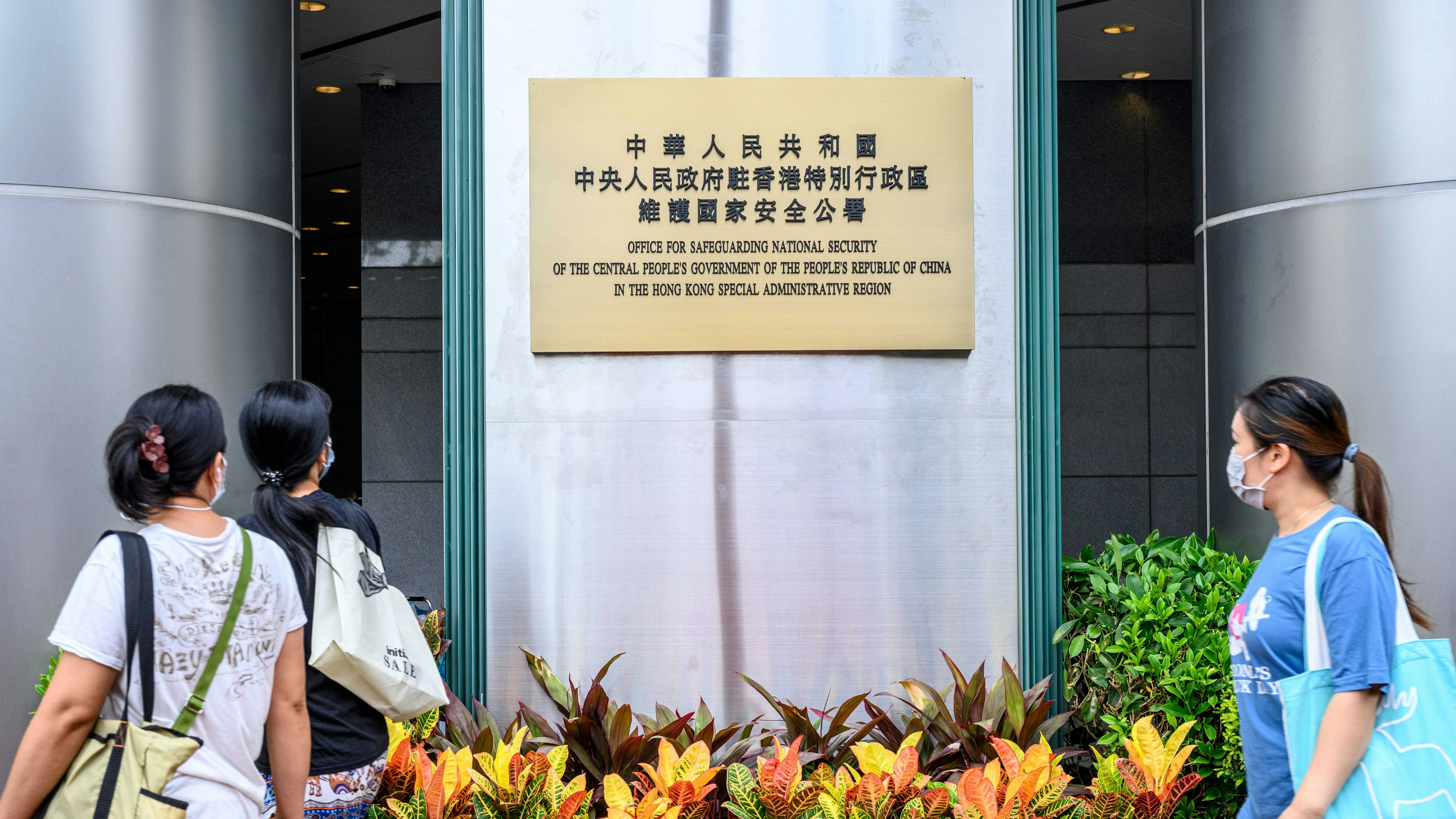 Pedestrians walk past a plaque outside the Office for Safeguarding National Security of the Central People's Government in the Hong Kong Special Administrative Region after its official inauguration in Hong Kong on July 8, 2020.