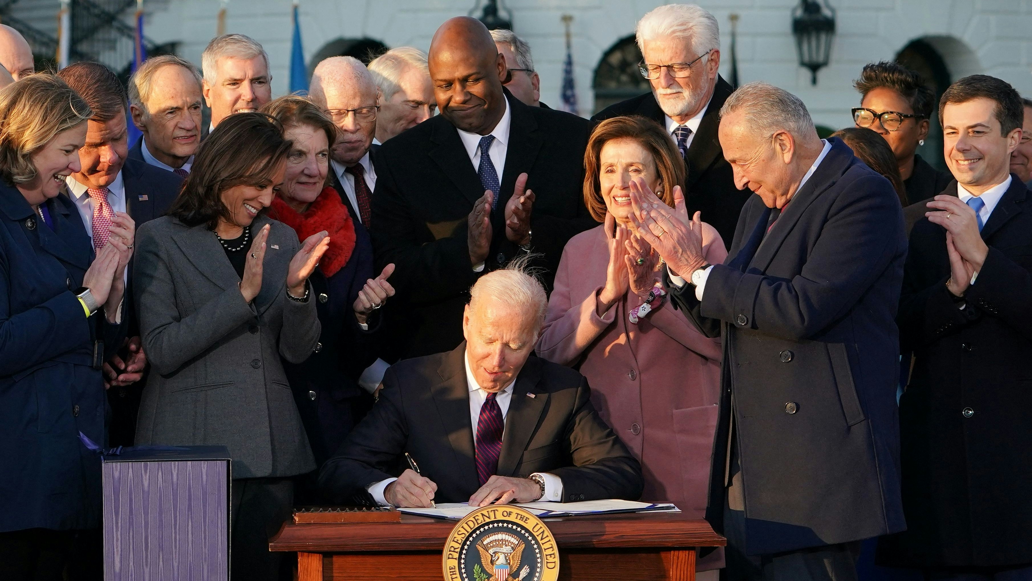 U.S. President Joe Biden signs the Infrastructure Investment and Jobs Act as he is surrounded by lawmakers and members of his Cabinet during a ceremony