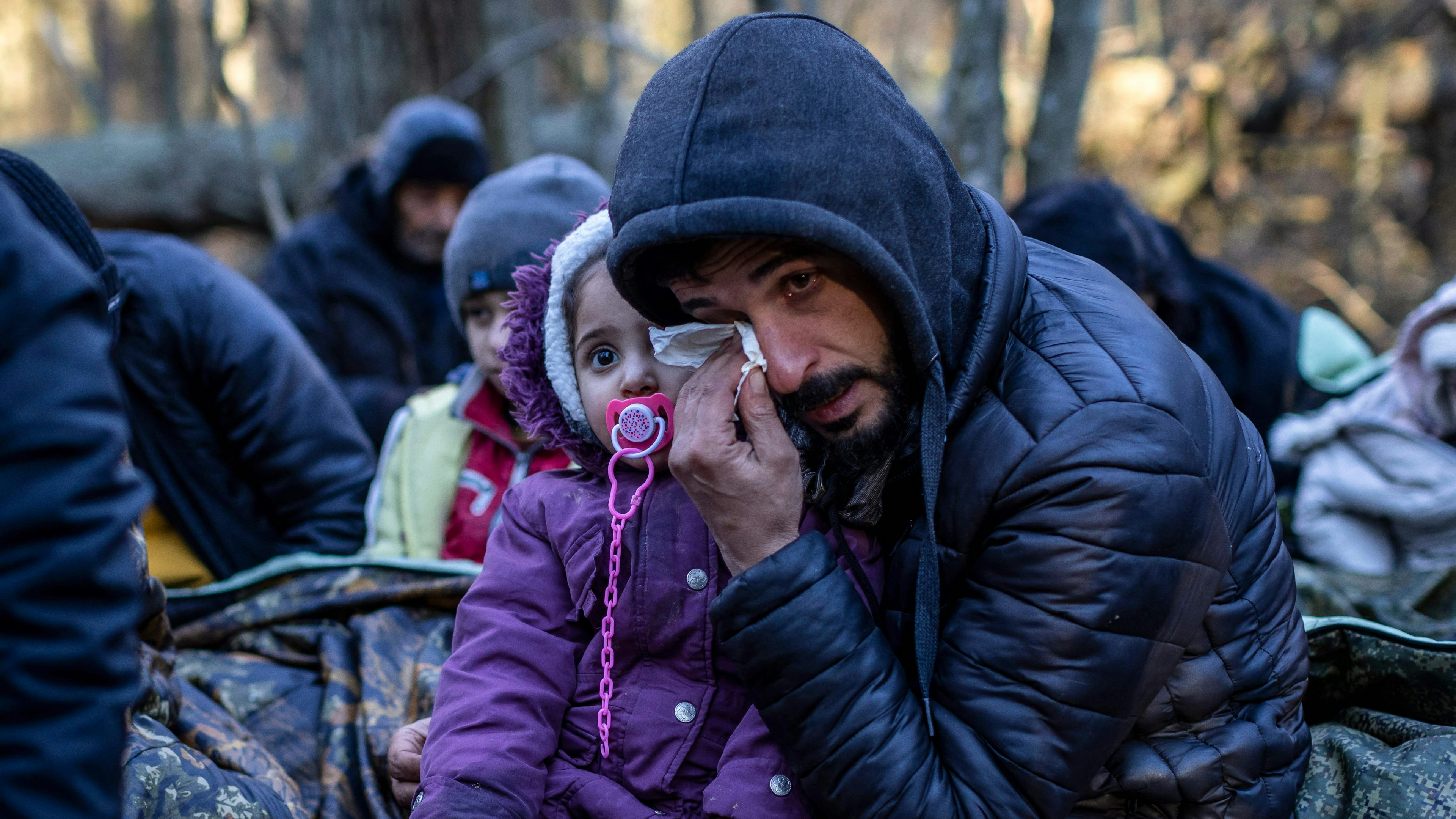 A man holding a child reacts as the members of the Kurdish family from Dohuk in Iraq wait for the border guard patrol, near Narewka, Poland
