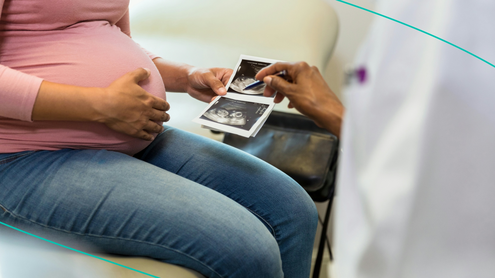 As the unrecognizable pregnant woman holds the ultrasound pictures, the unrecognizable female doctor uses her pen to point out details.