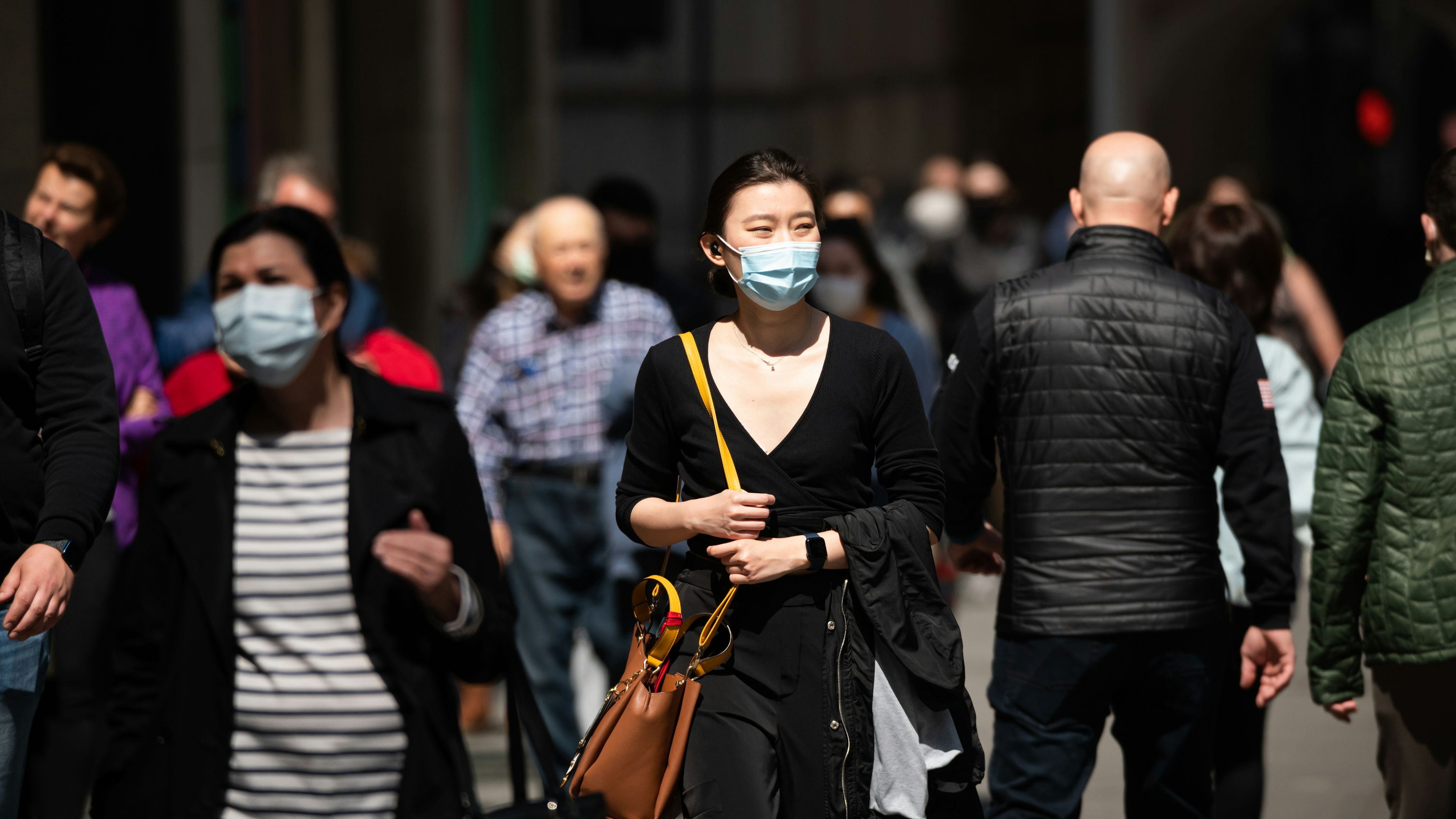 People wear face masks while walking in New York City.