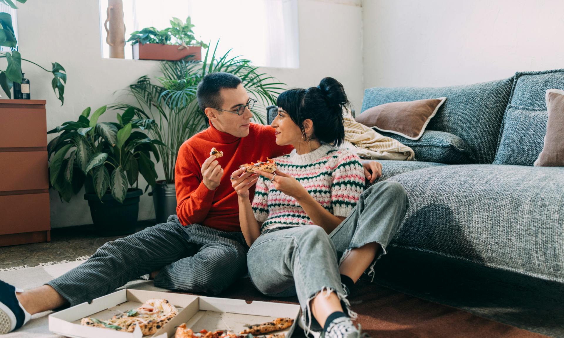 couple eating pizza together in living room