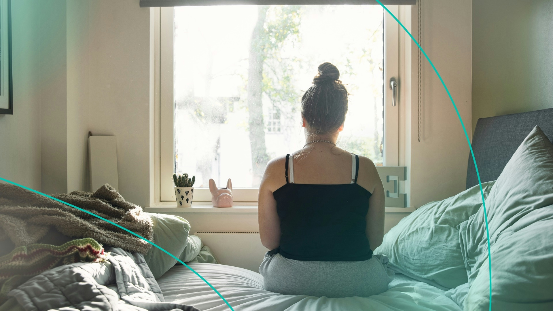 Woman looking out window sitting on bed