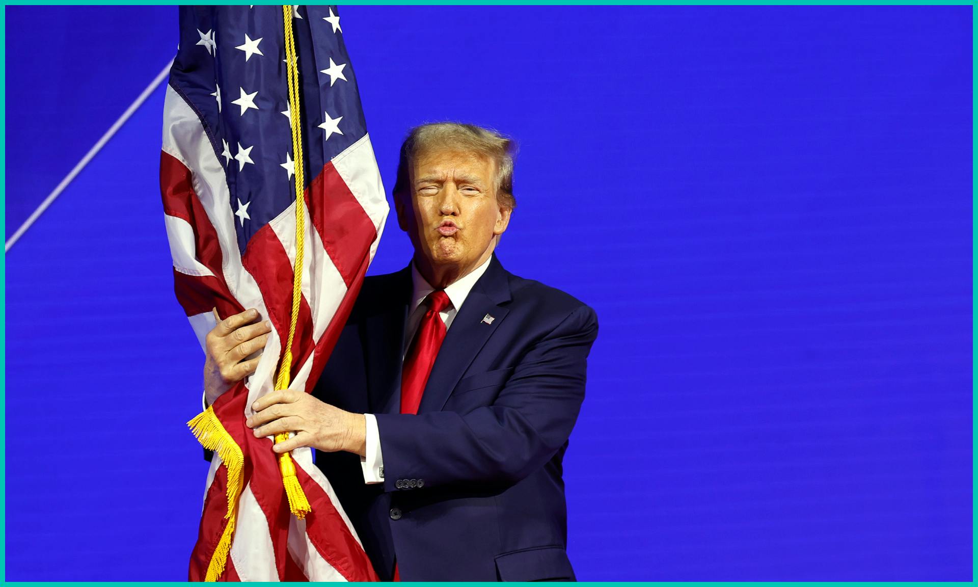 Republican presidential candidate and former U.S. President Donald Trump hugs an American flag as he arrives at the Conservative Political Action Conference 
