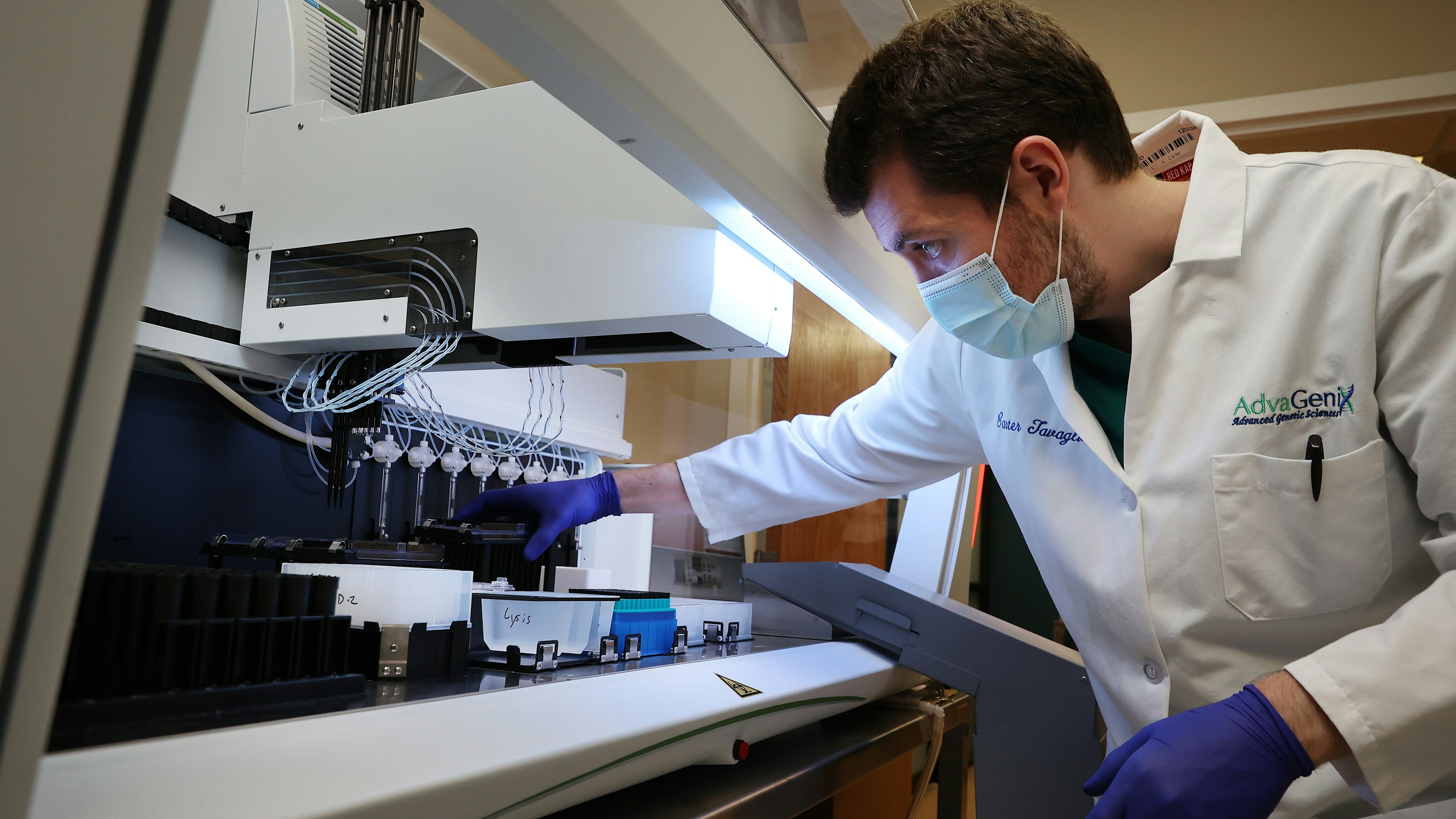 Lab Technician loads at Janus G3 automated workstation with coronavirus test samples