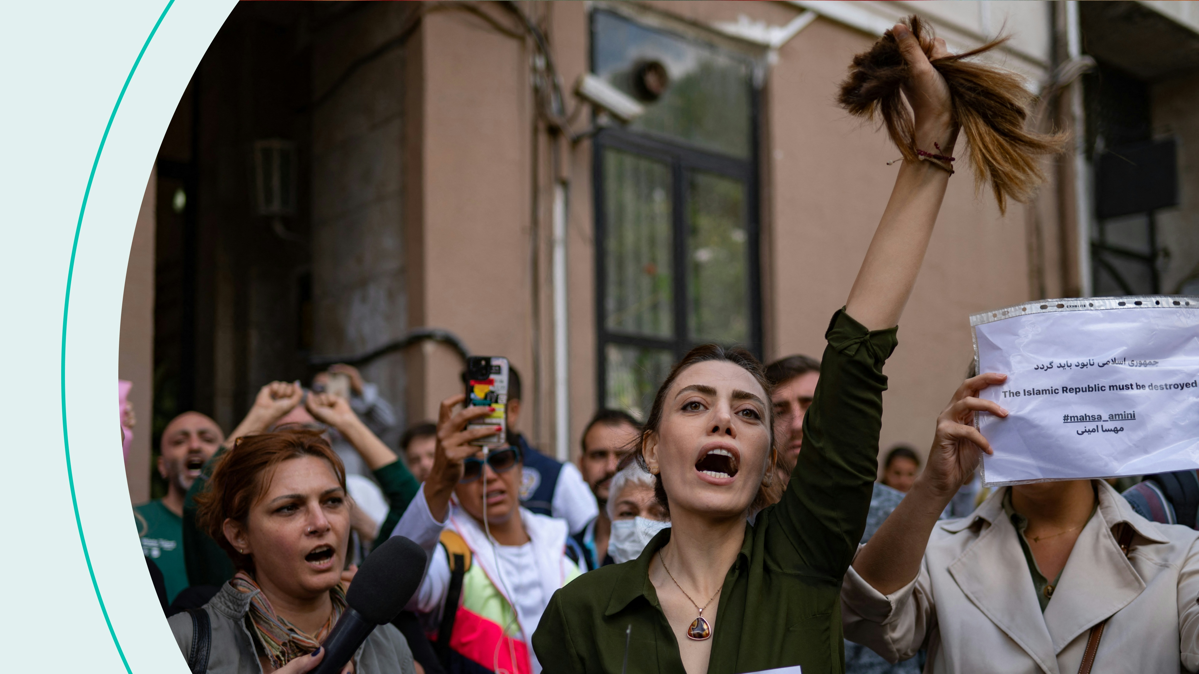 Nasibe Samsaei, an Iranian woman living in Turkey, holds up her ponytail after cutting it off with scissors, during a protest outside the Iranian consulate in Istanbul on September 21, 2022