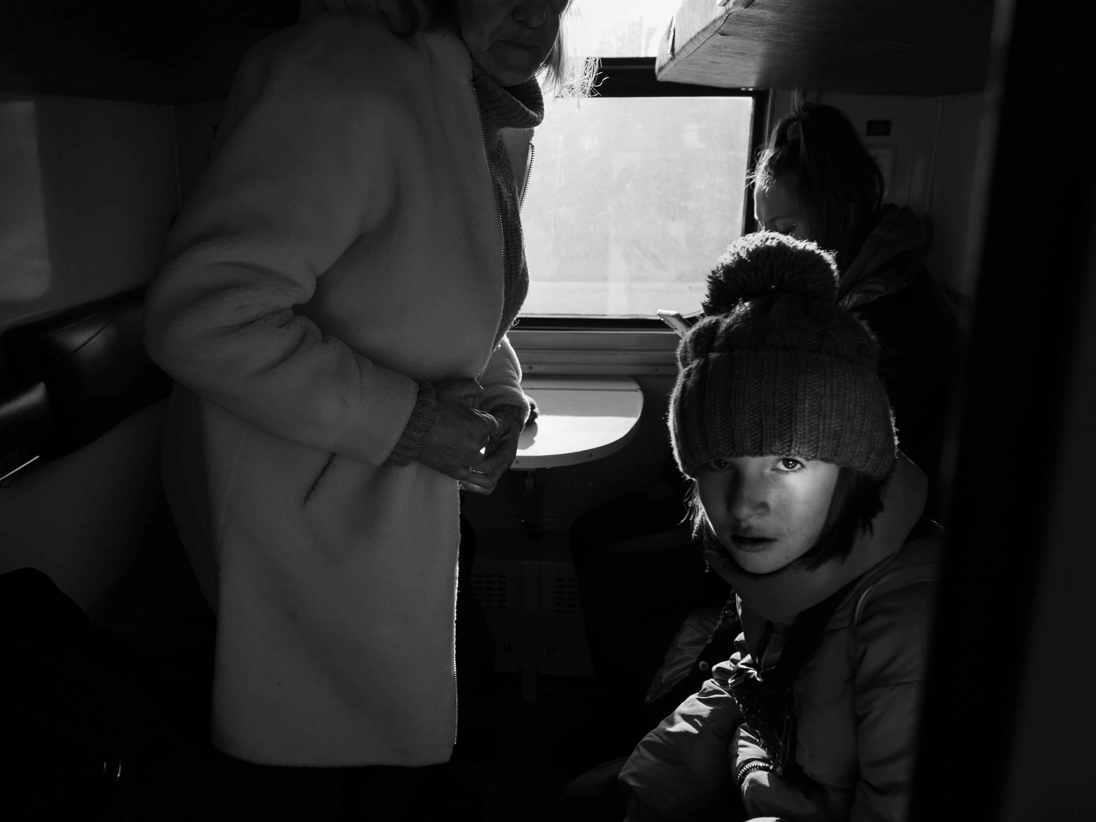 A portrait of a young girl with her family waiting to leave Lviv | Photo: © 2022 SVET JACQUELINE