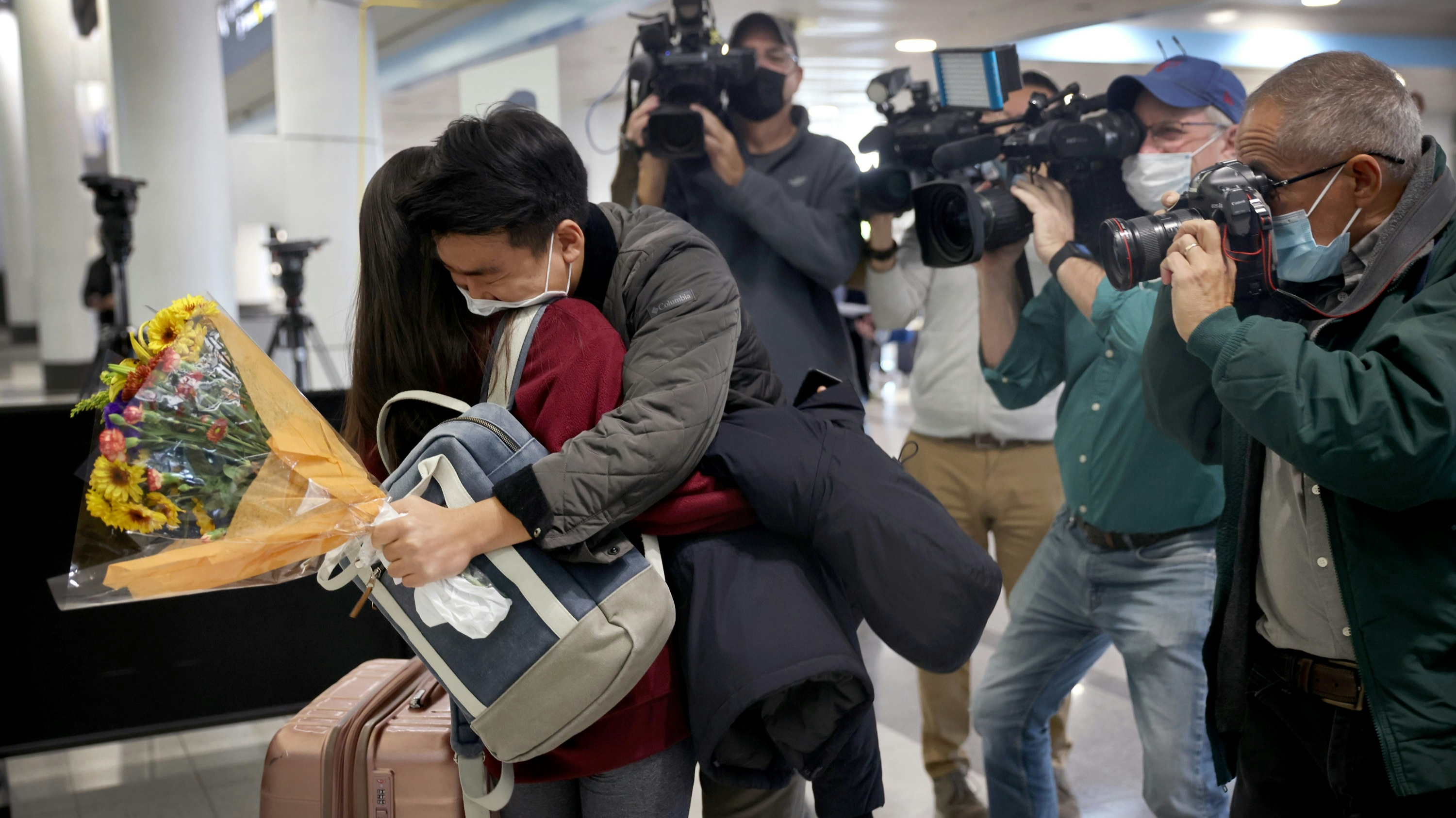 News crews gather around as Yerin Hong gets a hug from her boyfriend Soomin Kim after she arrived on a flight from Germany at the international terminal at O'Hare